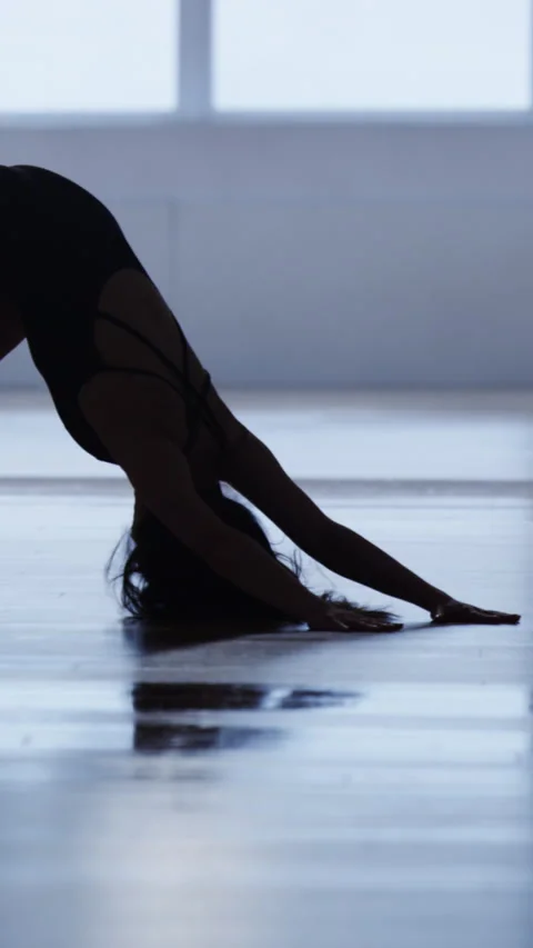 Practicing downward dog pose for a deep leg stretch in a bright indoor space Stock Footage 333510631