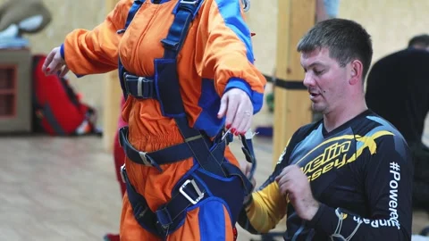 Practicing instructor checks the equipment before the tandem jump, tightens the Stock Footage 250014648