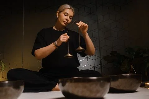 Practicing mindfulness and meditation with singing bowls in a serene indoor.. 스톡 사진