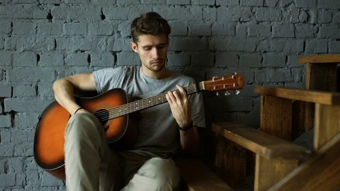 Practicing in playing guitar. Handsome young man playing guitar Stock Footage 69747664