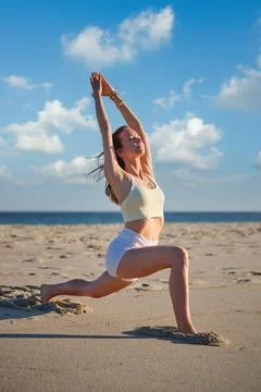 Practicing Warrior 1 pose at sunset on the beach Stock Photos
