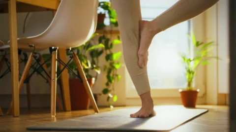 Practicing yoga at home with a focus on balance and relaxation in natural li Stock Footage 299039364