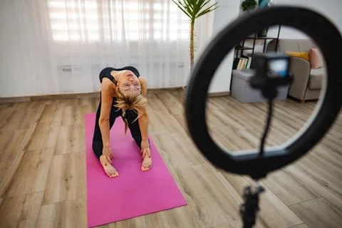 Practicing yoga indoors while streaming live to followers Stock Photos