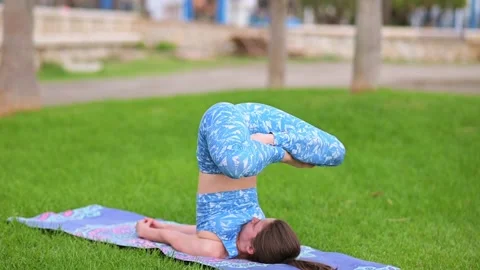 Practicing yoga in a serene beachfront park surrounded by palm trees at sunrise Stock Footage 292013355