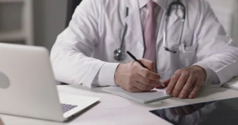 Practitioner doctor looking at laptop screen and giving consultations in video Stock Footage 148550818