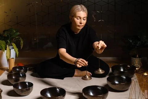 A practitioner engages in a sound healing session using singing bowls in a se Fotos de archivo