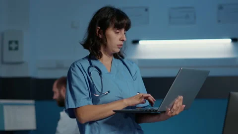 Practitioner nurse holding laptop computer analyzing patient illness report Stock Footage 221232271
