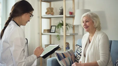 Practitioner with tablet visiting aged woman in her home Stock Footage 113997277