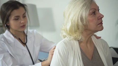 Practitioner using stethoscope and visiting senior woman at home Stock Footage 113997951