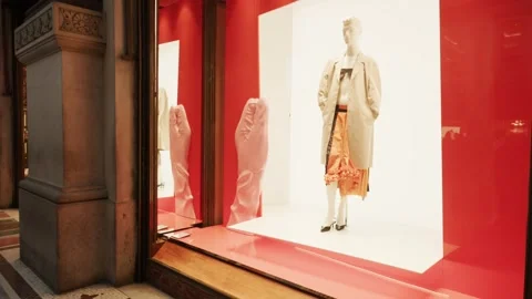 Prada SS26 window display features a chic mannequin in vibrant spring attire, Stock Footage 330033613