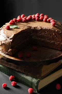 Prague cake. Chocolate cake with raspberries and books. Cake on a dark backgr Stock Photos