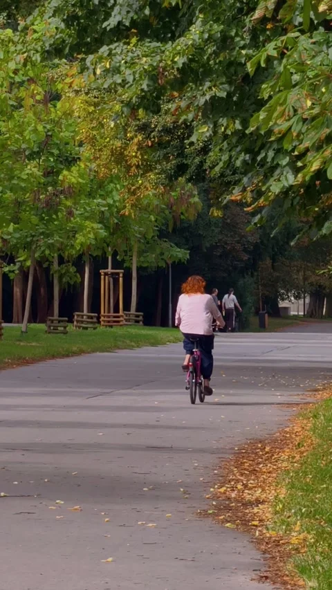 PRAGUE, CZECH REPUBLIC – AUGUST 28, 2026: Woman rides a bicycle through a park 스톡 동영상 343923771