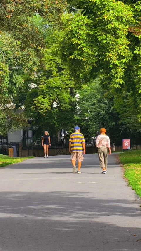 PRAGUE, CZECH REPUBLIC – AUGUST 28, 2026: People walk along a green park path Vídeo Stock 343923970