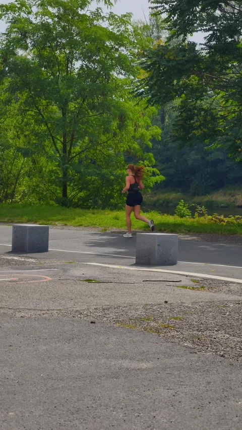 PRAGUE, CZECH REPUBLIC – AUGUST 28, 2026: Woman running along a green park Vídeo Stock 343926549