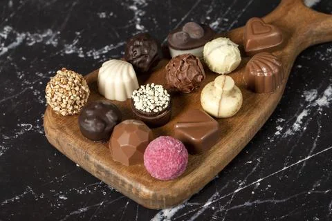 Praline Chocolate. Assorted truffles or praline chocolates on wood serving bo Stock Photos
