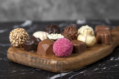 Praline Chocolate. Assorted truffles or praline chocolates on wood serving bo Stock Photos