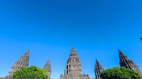 Prambanan Temple spires form a dramatic skyline above green trees beneath a.. Stock-Fotos
