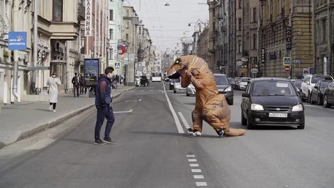 Pranker in t rex costume running at city street crosswalk Stock Footage 84929677