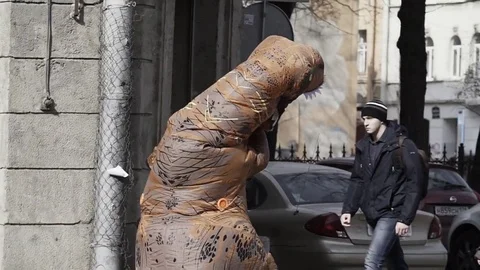 Prankster in t rex costume in crowd of people running on city sidewalk Stock Footage 84928685