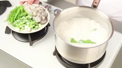 Prawns, mange tout and spring onions being added to coconut milk soup Stock Footage 24672482