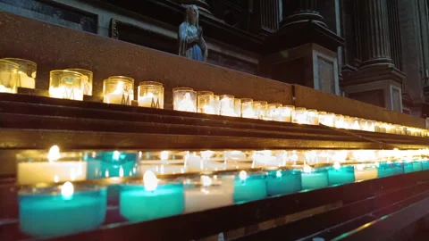 Prayer candles light a dark cathedral with a statue Stock Footage 336603666