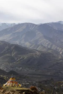 Prayer flag draped stupa overlooking a terraced valley, Tongren County, Lon.. Stock-Fotos