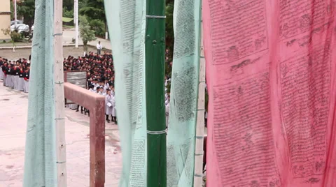 Prayer flags blowing in wind in front of school children 스톡 동영상 37163964