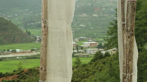 Prayer flags blowing in wind with village in background 스톡 동영상 37164025