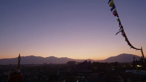 Prayer flags fluttering in the wind against a city at dusk Stock Footage 113254919