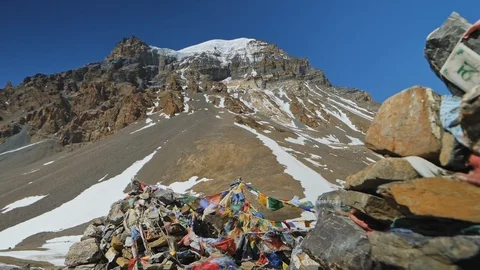Prayer flags sway at Thorong La highland pass, snowy rock Yakawa Kang mountain Stock Footage 127080591