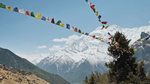 Prayer flags sway in wind, Annapurna II snow face nearby Ghyaru village, Nepal Stock Footage 124677358