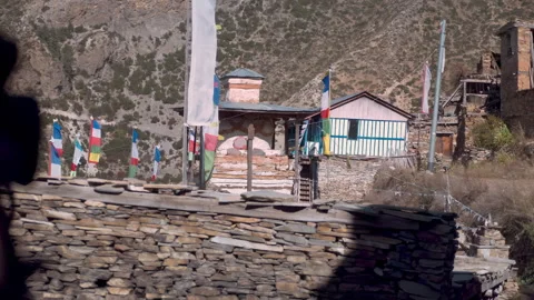 Prayer flags sway in wind in front of Annapurna II snow face nearby Ghyaru villa Stock Footage 294613546