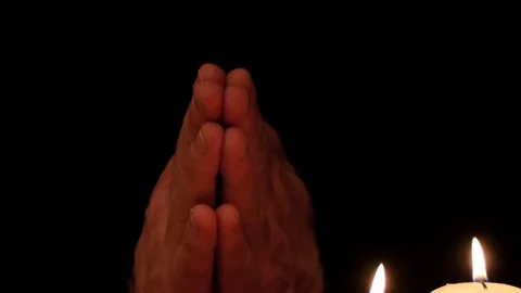 Prayer hands on black background with candles closeup smooth zoom Stock Footage 77544092