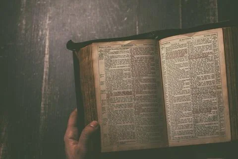 Prayer, man hands over an old open book Holy Bible, wooden desk background. Stock Photos