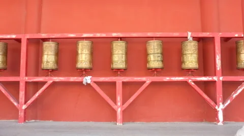 Prayer wheels rolling against a red wal Stock Footage 40546152
