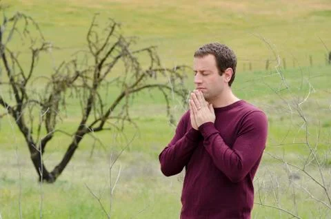 Praying alone in an empty field. Stock Photos