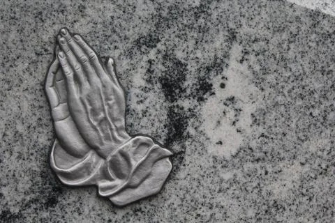Praying hands on a gravestone Stock Photos