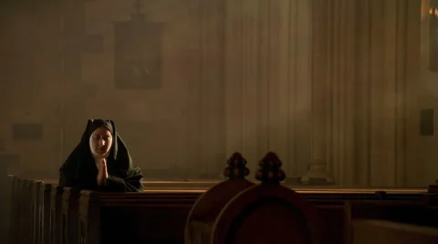 Praying nun kneeling among sun rays in empty church Video stock 59249829