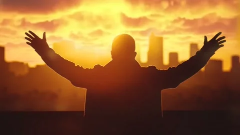 Praying over city with arms uplifted to sky at sunset in worship to God Stock Footage