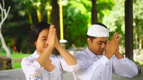 Praying with putting hands to forehead. Young family in Bali pray in temple. Stock Footage 128332465