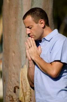 Praying by a tree outdoors. Stock Photos