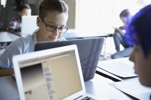 Pre-adolescent boy programming at laptop in classroom Foto stock