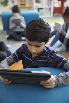 Pre-adolescent boy using digital tablet in library Stock Photos
