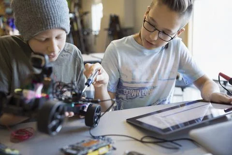 Pre-adolescent boys assembling and programming robotics at digital tablet in cla 스톡 사진