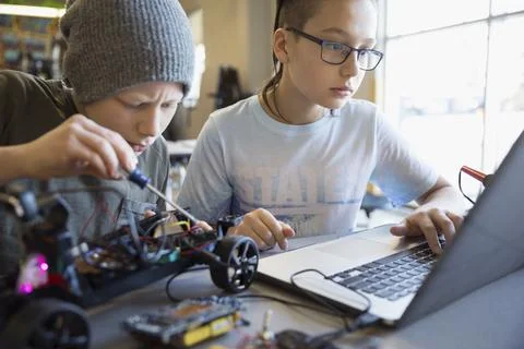Pre-adolescent boys assembling and programming robotics at laptop in classroom 스톡 사진