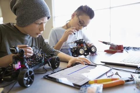 Pre-adolescent boys assembling and programming robotics at digital tablet in cla Stock Photos
