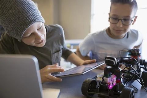 Pre-adolescent boys assembling and programming robotics at digital tablet in cla 스톡 사진