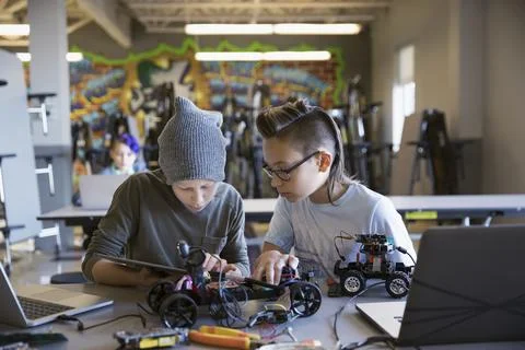Pre-adolescent boys assembling and programming robotics at digital tablet in cla 스톡 사진