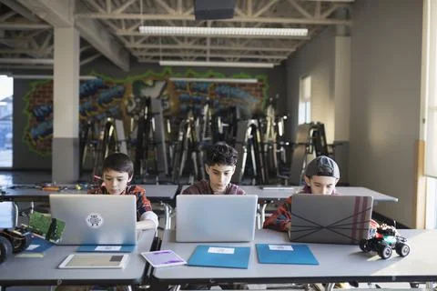 Pre-adolescent boys programming robotics at laptops in classroom 스톡 사진