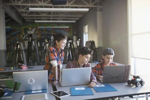 Pre-adolescent boys programming robotics at laptops in classroom 스톡 사진